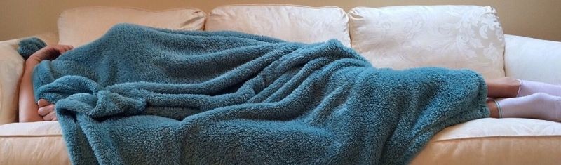 Woman sleeping under blanket on couch